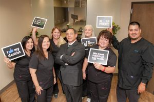 our dentist and team holding signs about the practice