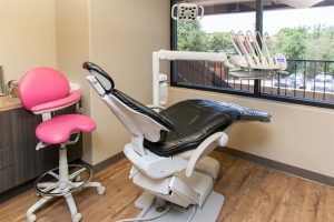 dental office operatory photo with dental chair and pink chair for staff
